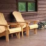 Two chairs on the porch of a cabin.