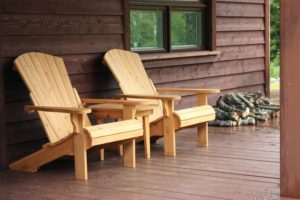 Two chairs on the porch of a cabin.