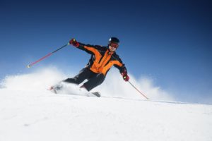 A man in an orange jacket skiing.