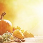 A pumpkin and other Thanksgiving decorations on a table.