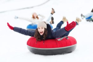 A girl snow tubing down a slope with her friends.