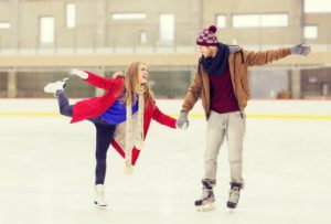 A couple holding hands and ice skating.