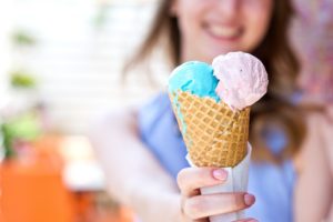 A woman holding a waffle cone with two scoops.