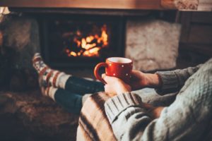 woman holding coffee mug in front of fire