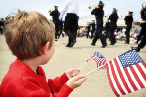 boy holding flags watching parade
